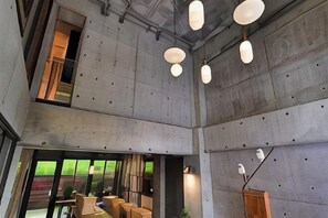 En modern inredning med betongväggar, hängande taklampor och ett tydligt avgränsat sittområde med bord och stolar.
