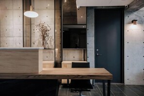A reception area with a wooden reception desk, a black bench, and a wall-mounted light fixture. - Meet Sun Moon Lake (Nantou)