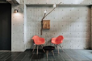 A room with a concrete wall, two red chairs, a small wooden cabinet, and a branch with white flowers. - Meet Sun Moon Lake (Nantou)