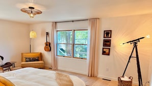 Un dormitorio con una cama, una guitarra, un telescopio y una ventana con cortinas.