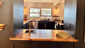 Una cocina moderna con una isla central, doble pileta y un amplio ventanal que proporciona luz natural.