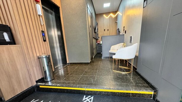 A hotel entrance with a black doormat reading "KAA HOUSE HOTEL" and a reception area with a modern design, including a counter and seating. - Kaa House Hotel (Carmopolis de Minas)