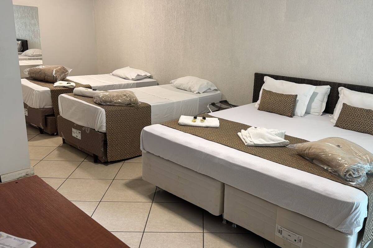 Quarto de hotel com duas camas de solteiro, uma cama de casal e um sofá-cama.