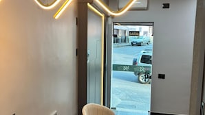 A modern reception area with a curved light installation on the wall, a reception desk, and two chairs. - Kaa House Hotel (Carmopolis de Minas)