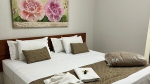A neatly made bed with white linens, a patterned throw, and a decorative pillow. - Kaa House Hotel (Carmopolis de Minas)