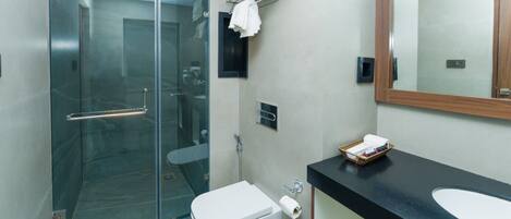 A modern bathroom with a glass shower enclosure, a white toilet, a black countertop with a sink, and a mirror.