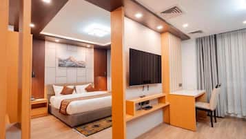 Una habitación de hotel moderna con cama, televisor, escritorio y espacios de almacenamiento.