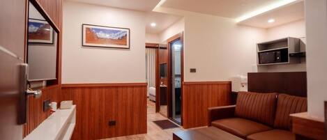 A modern room with a wooden floor, a sofa, a coffee table, a microwave, and a framed picture on the wall.