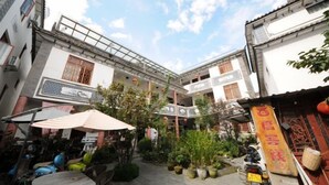 A courtyard with traditional architecture, potted plants, and a scooter parked outside.