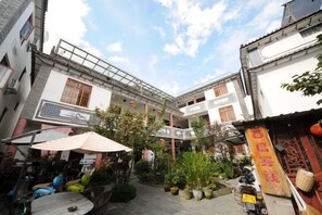 A courtyard with traditional architecture, potted plants, and outdoor seating.