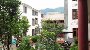 A courtyard with traditional architecture, potted plants, and a scooter.