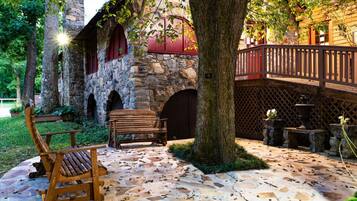 A stone building with a wooden deck, a bench, and potted plants.