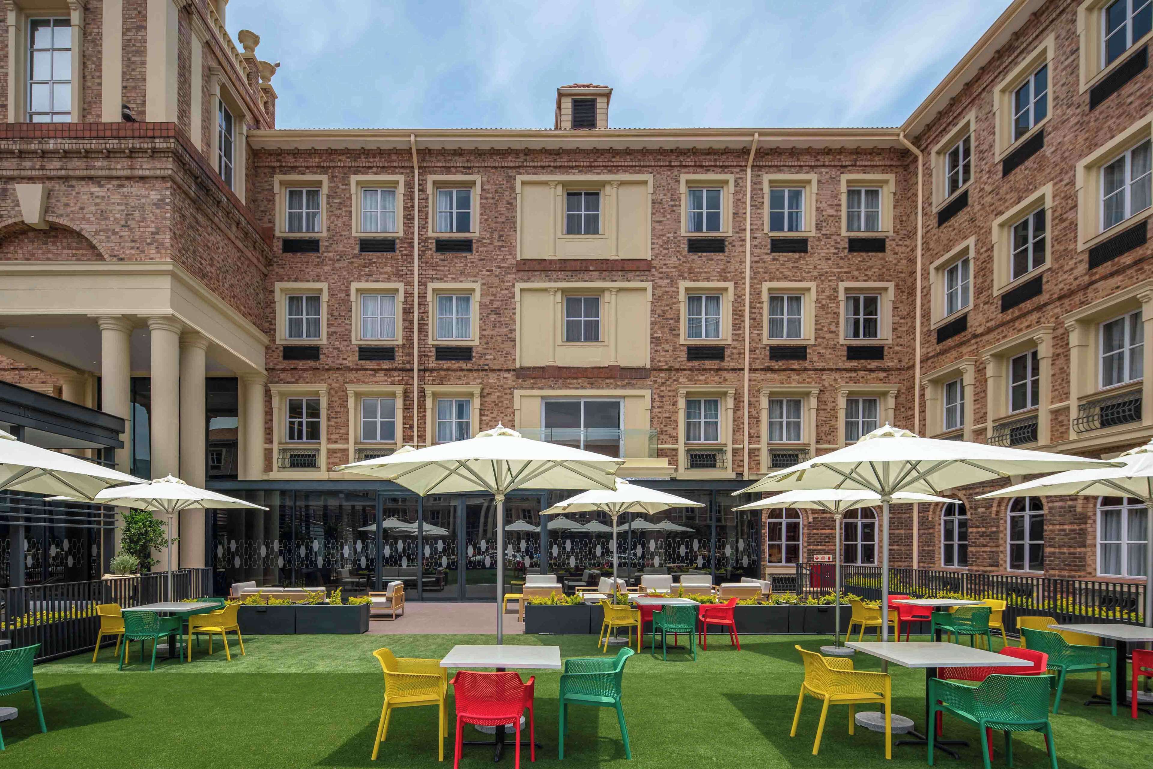 A courtyard with outdoor seating, brick buildings, and a clear sky.