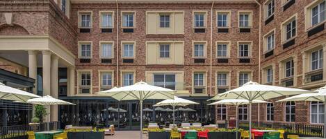 A courtyard with outdoor seating, brick buildings, and a clear sky.