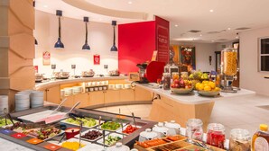 Ein Buffet mit verschiedenen Speisen, Beilagen, einer Obstschale und einer Kaffeestation.