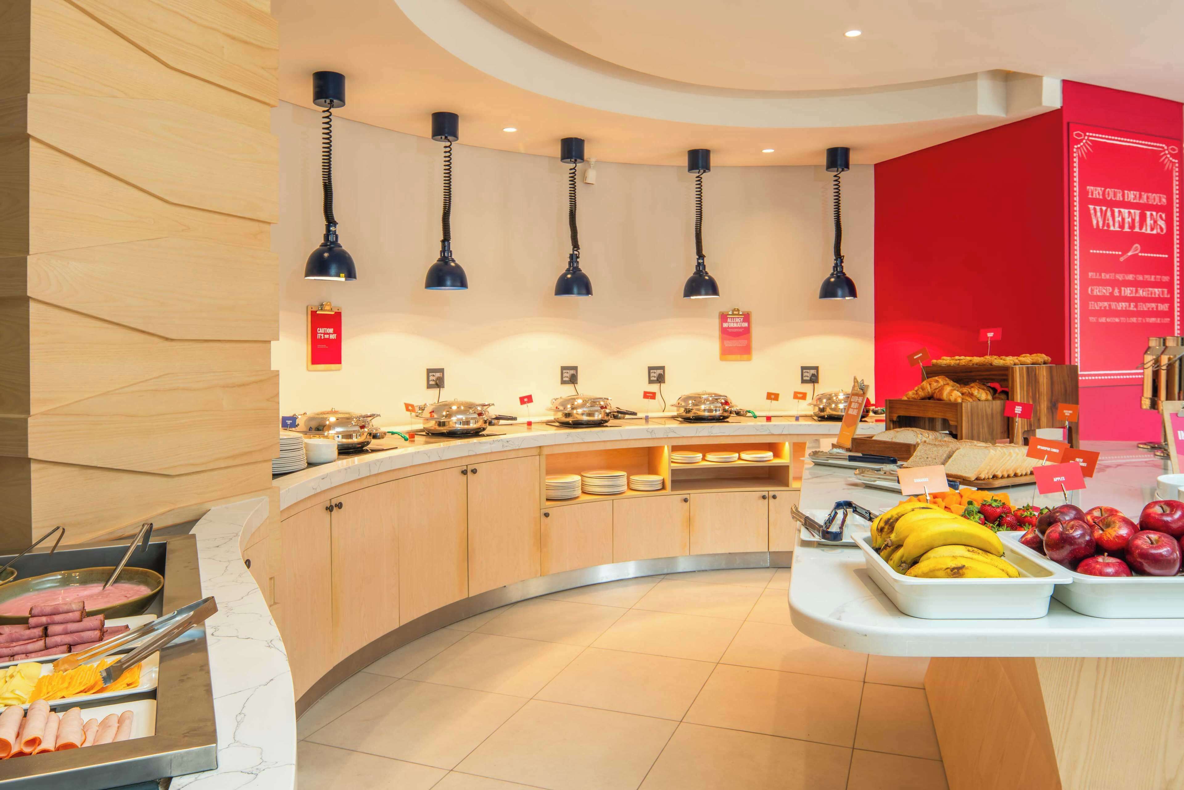 Zona de bufé con diversas opciones de comida, incluyendo frutas y una estación de gofres.