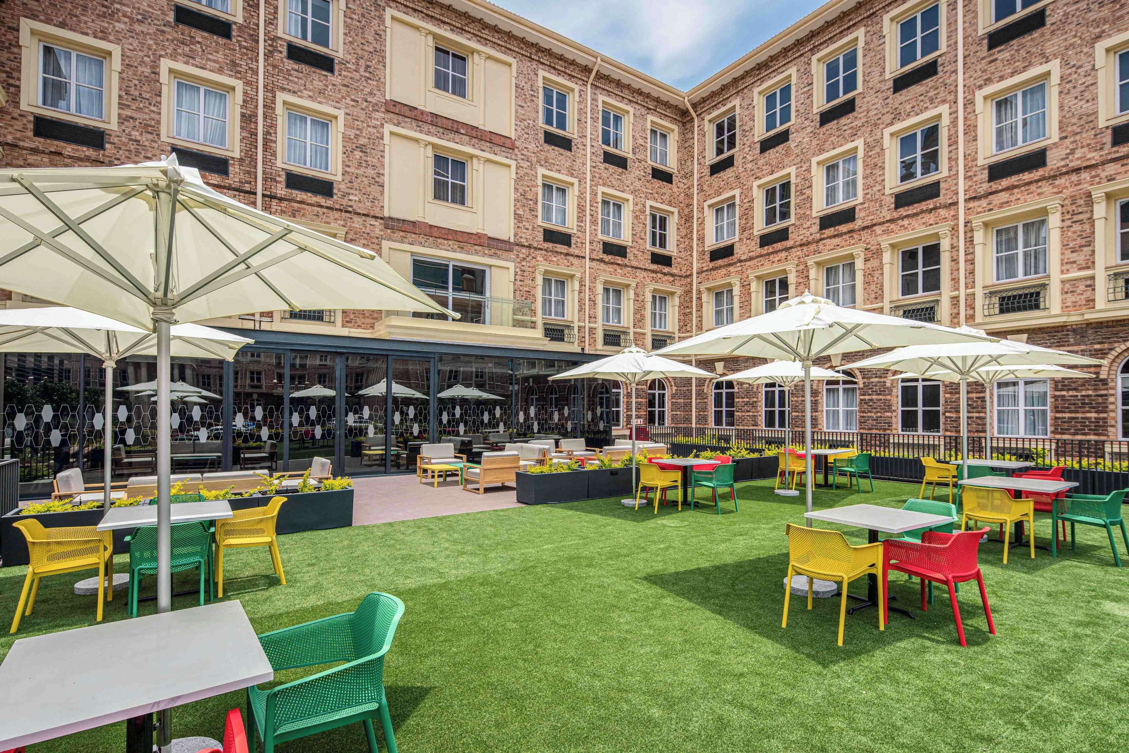 A courtyard with outdoor seating, a bar, and a brick building in the background.