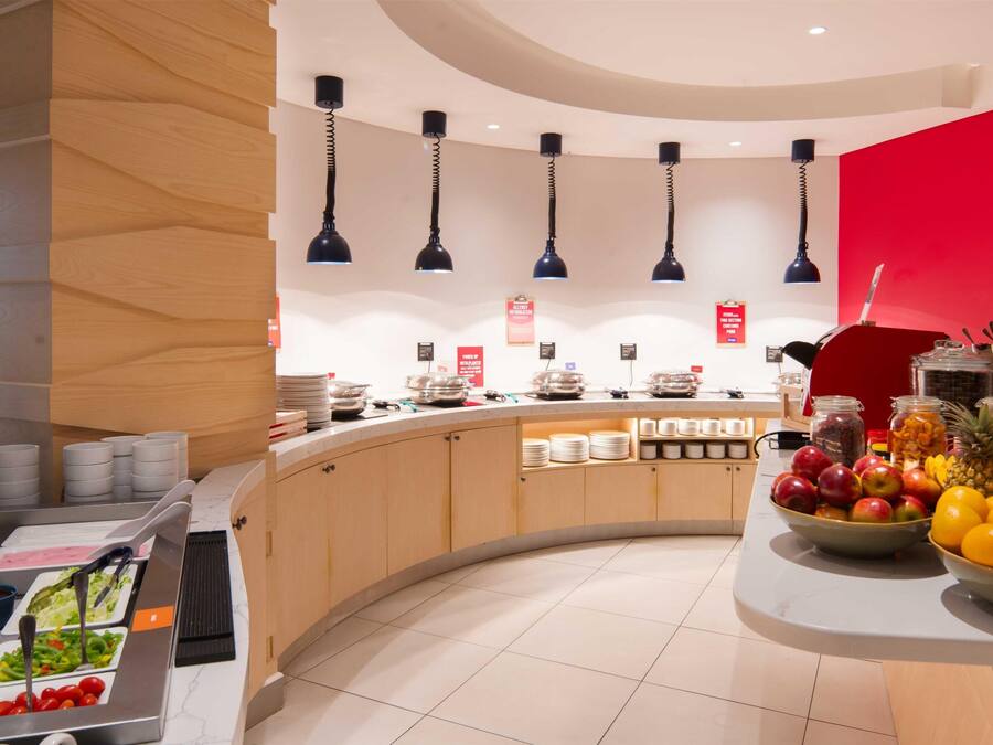 A modern breakfast bar with a curved design, featuring a variety of food items and a fruit bowl.