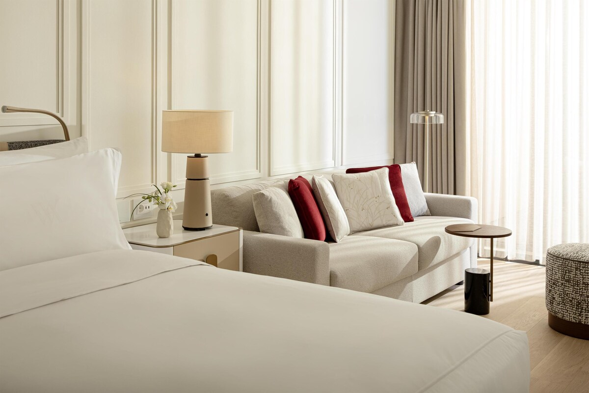 Hotelkamer met een groot bed, een bank, een nachtkastje met lamp en een klein tafeltje.