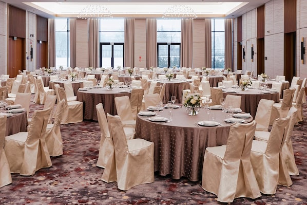 A large banquet hall with round tables, chairs, and floral centerpieces. - Waldorf Astoria Minsk (Minsk)