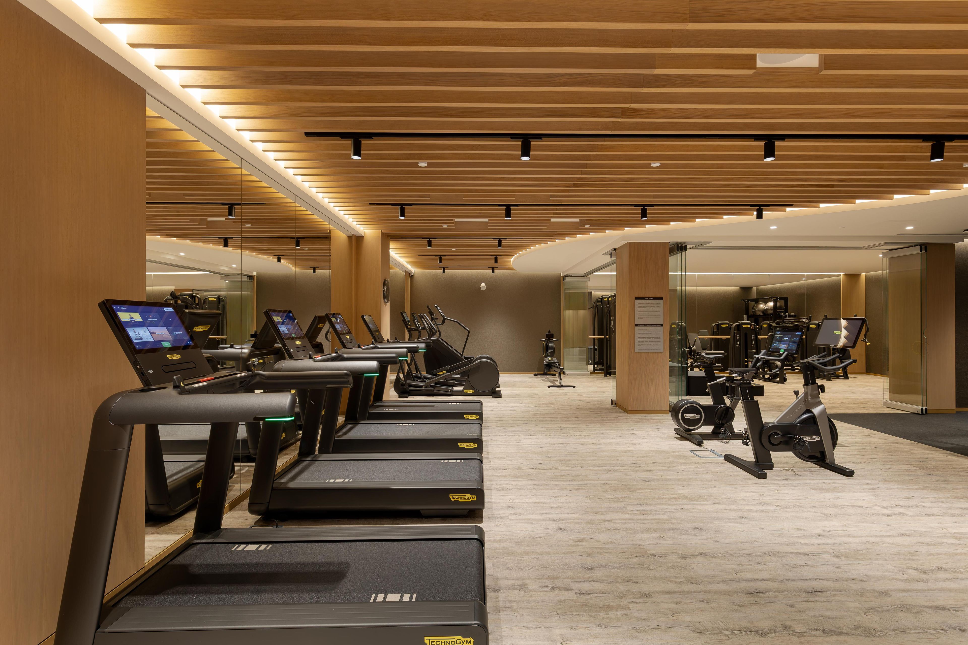 A modern gym with multiple treadmills, stationary bikes, and exercise equipment.