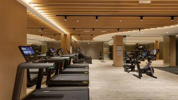 A modern gym with multiple treadmills, stationary bikes, and exercise equipment.