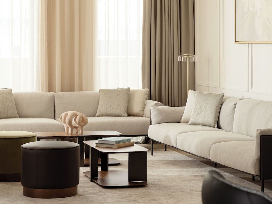 Ein modernes Wohnzimmer mit einem Ecksofa, Poufs, einem Couchtisch und einer Stehlampe.