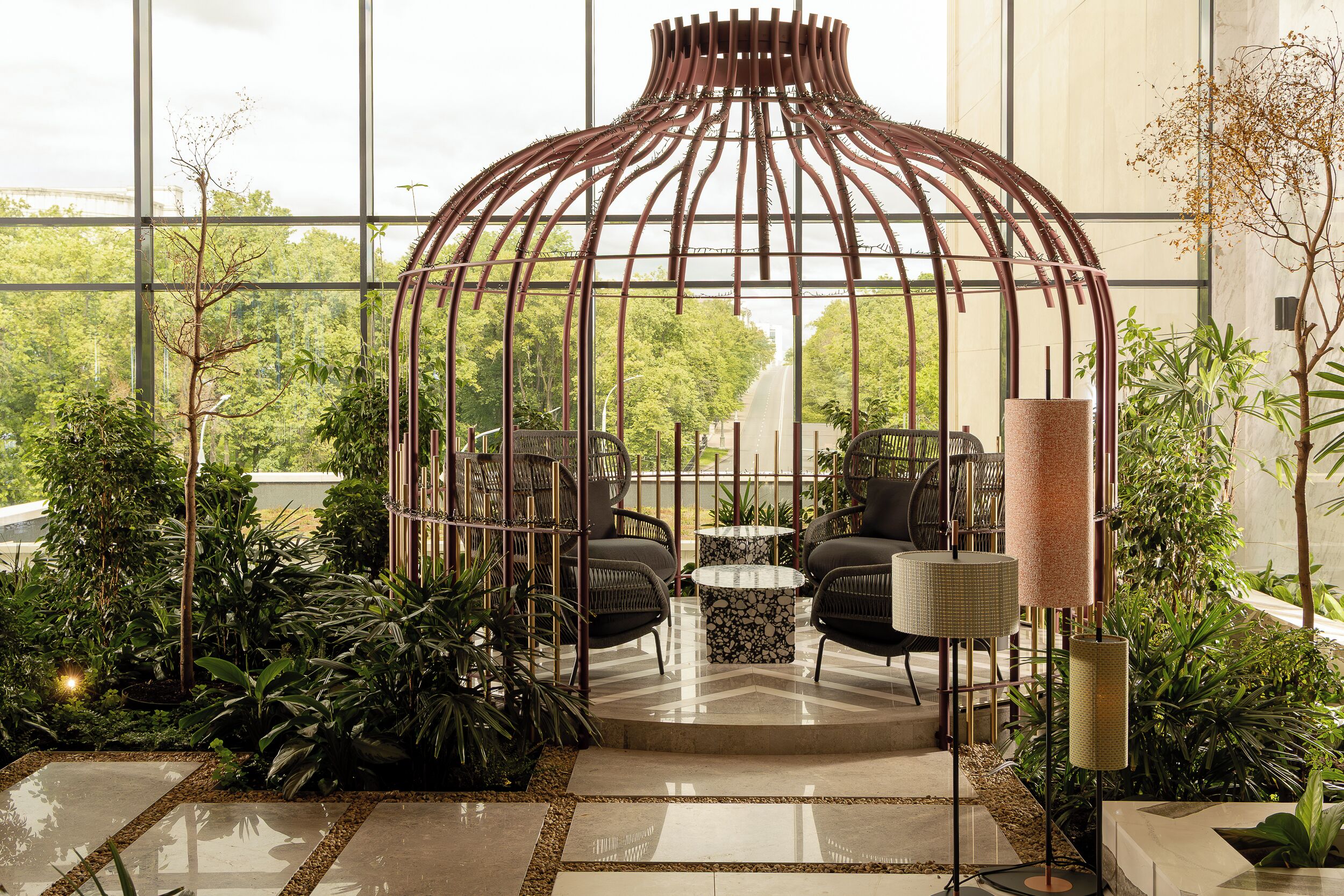 A modern indoor garden with a bamboo structure, seating area, and potted plants.