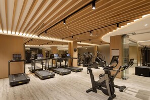 Une salle de sport moderne équipée de tapis de course, d’appareils elliptiques et de vélos d’exercice.