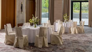 Uma sala de banquetes com mesas redondas, cadeiras e centros de mesa florais.