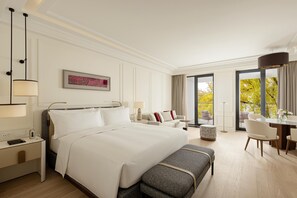 Une chambre d’hôtel avec un grand lit, des tables de chevet, un bureau et une vue sur les arbres par la fenêtre.