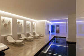 Een moderne spa met een lange zitbank, een zwembad en een receptiebalie op de achtergrond.