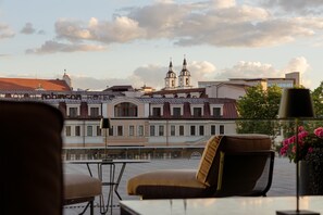 Eine Terrasse mit Blick auf ein historisches Gebäude mit zwei Türmen, ein modernes Gebäude und ein Restaurant namens 'ROBINSON'.