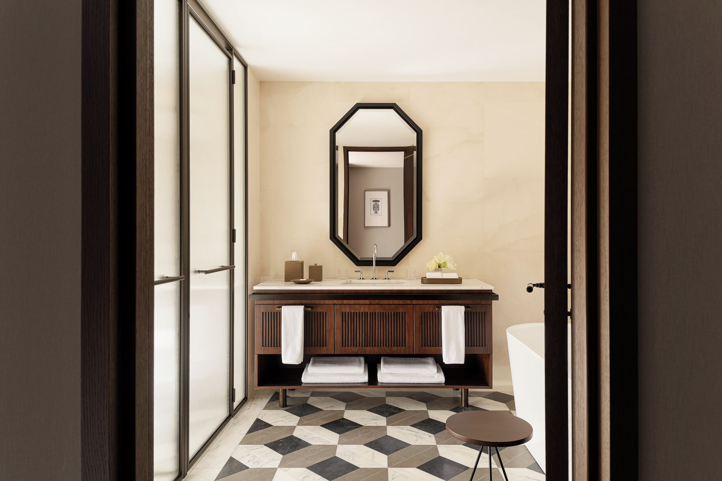 Une salle de bain moderne avec un grand miroir, une baignoire et un sol carrelé.