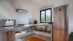 A compact kitchen with a built-in stove, a refrigerator, and a window. - Jungle View Penthouse apt w Pool & Private Rooftop (Sayulita)
