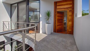A modern building with a glass facade, a wooden door, and a metal staircase. - Jungle View Penthouse apt w Pool & Private Rooftop (Sayulita)