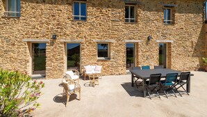 Ein Steinhaus mit einer Terrasse, auf der ein Tisch und Stühle stehen.