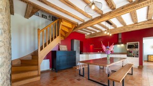 Eine geräumige Küche mit einer Holztreppe, einem Esstisch mit Bänken und einer roten Akzentwand.