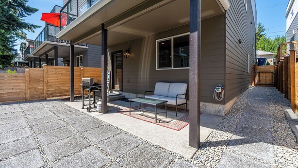 Un patio techado con zona de estar, una parrilla y una valla de madera.