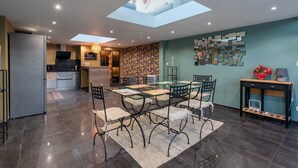 A modern kitchen with a skylight, a dining area with a glass table, and a patterned wall.