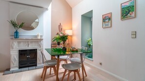 A modern dining area with a glass table, wooden chairs, a fireplace, and artwork on the walls. - Le petit Cocon d'Auray - Duplex, proche port St goustan (Auray)
