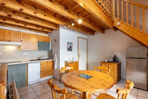 A wooden interior with a kitchen, dining area, and staircase.