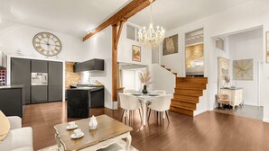 Una sala de estar moderna con una mesa de comedor, una araña y una cocina al fondo.