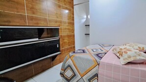 A bedroom with a bed, pillows, a TV, and a tiled wall. - Apartamento 2 Praia Morro de São Paulo  (Cairu)
