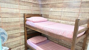 A bunk bed with pink bedding in a room with wooden walls and a white fan. - Apartamento 2 Praia Morro de São Paulo  (Cairu)