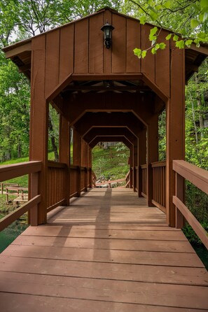 Un pont en bois couvert, doté d’une allée centrale et de garde-corps de chaque côté, et entouré de verdure.