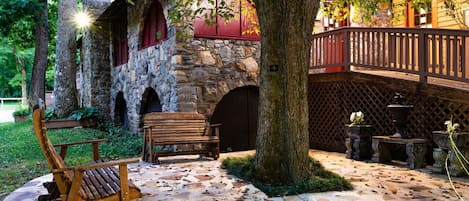 A stone building with a wooden deck, a bench, and potted plants.