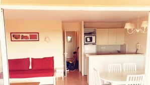 A compact living space with a kitchenette, a dining area, and a red sofa. - A little cocoon in Provence on the Pont Royal golf course (Mallemort)