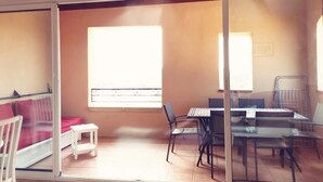 A room with a sliding glass door, a small white table, a red sofa, and a dining area with a table and chairs. - A little cocoon in Provence on the Pont Royal golf course (Mallemort)