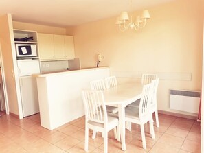 A compact kitchen with a microwave, stove, and a small island with chairs.